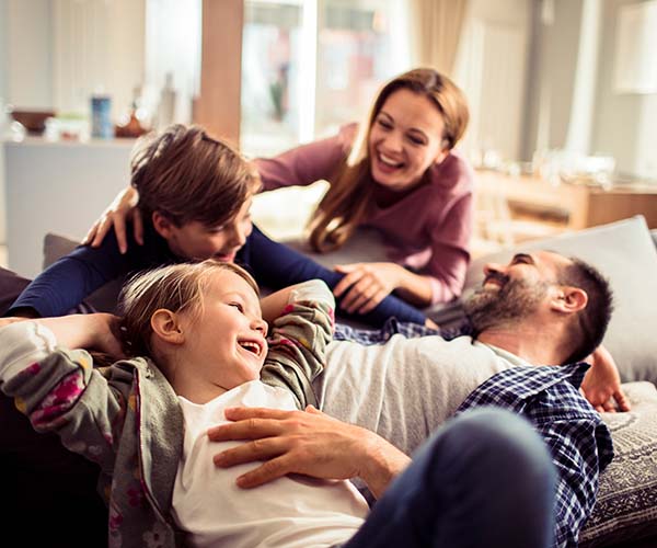 Семейство с две деца се смеят.