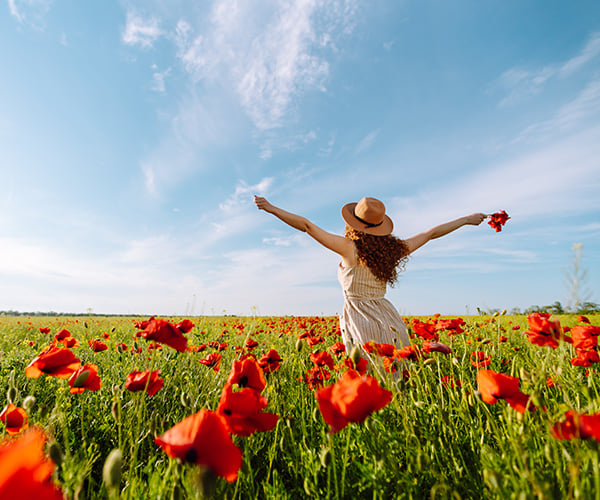 Жена на поляна от пролетни цветя, червени магове.