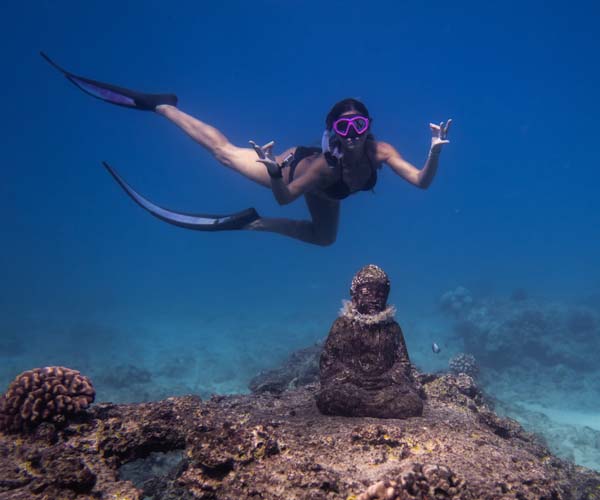 гмуркач под вода със статуя