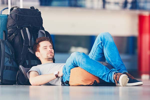 Турист спи отпрян на раницата си, изморен от часовата разлика