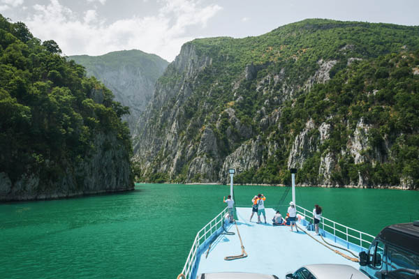 Хора на разходка с лодка по езерото Комани в Албания