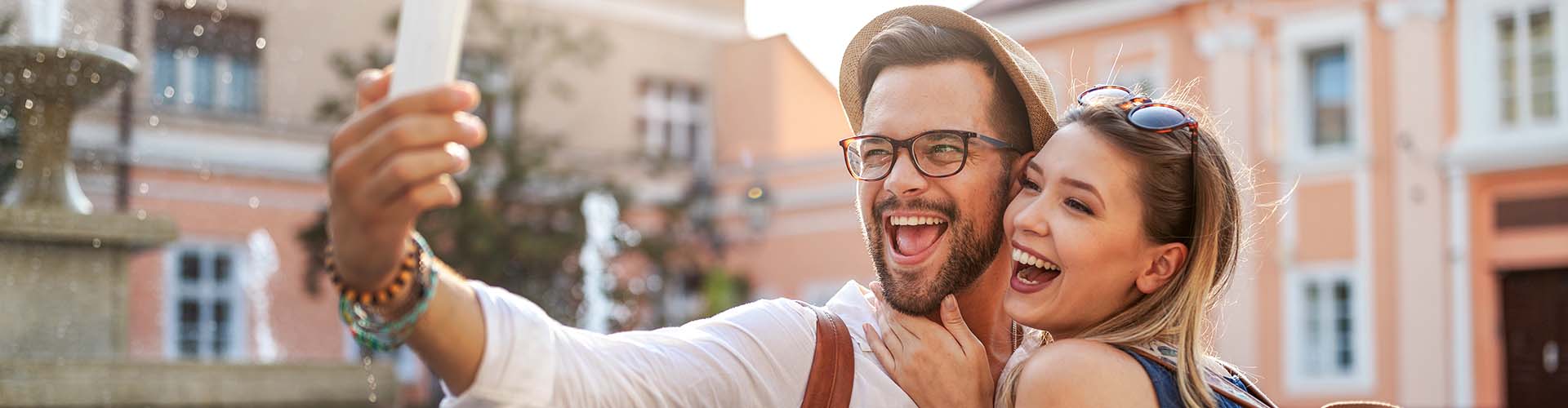 Туристическа двойка се усмихва на камерата, наслаждавайки се на почивката си с годишна застраховка за пътуване