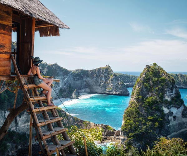 Туристка на почивка, седяща на стълба с излед към морето