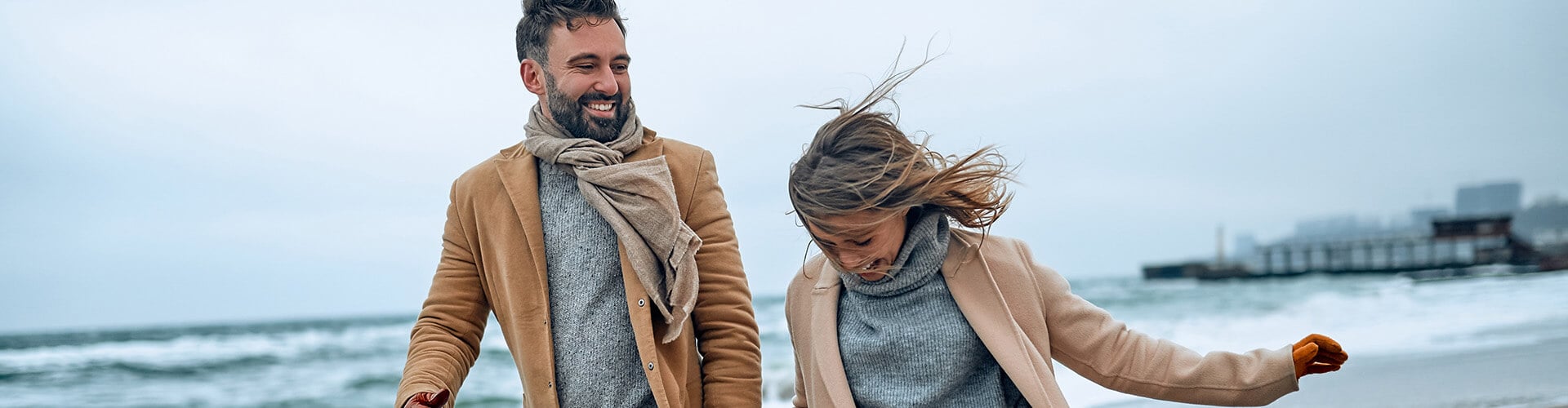 Застраховка при отмяна на пътуване, усмихната двойка на разходка по плажа