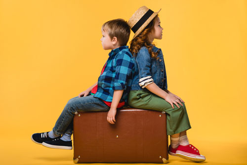 Две деца седящи върху куфар
